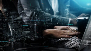 התמונה מתארת אדם שעובד על מחשב נייד בסביבה משרדית, כשברקע נראה נוף עירוני ומעליו מונחים קוד מחשבים שונים.